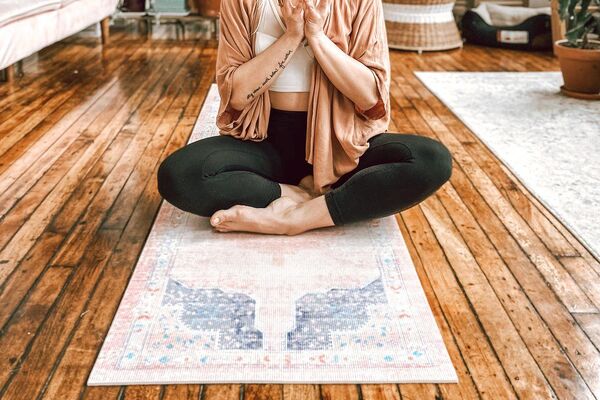 Person sitting on a yoga mat in a softly lit room at dusk
